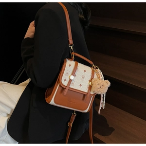Detail of mini brown and white backpack with bear pattern, silk scarf, and plush charm