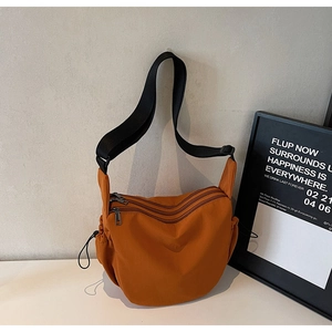 Close-up of vibrant orange nylon crossbody bag with multi-layer zippers and side drawstring
