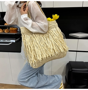 Détail du sac cabas en paille d'été avec de longues franges et un design de plage