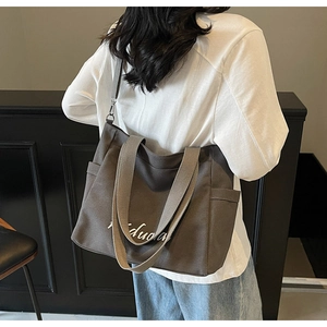 Detail of dark brown canvas tote bag with adjustable strap and Kiduola lettering
