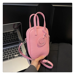 Detailed shot of a pink pebbled leather handbag with smiley tag and silver hardware