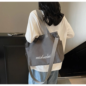 Detailed back view of a grey canvas tote bag with wide shoulder strap and side pocket