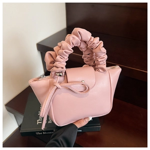 Close-up of pink pleated handbag showing ribbon bow detail and silver metal zipper