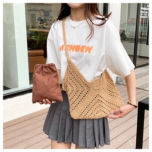 Detail of hand-woven straw tote bag with wide strap and brown drawstring inner pouch