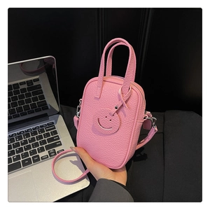 Detail of pink pebbled leather handbag featuring a cute smile charm and silver hardware