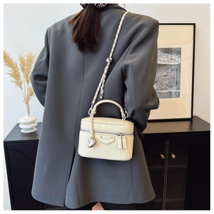Detailansicht der cremeweißen Leder-Box-Tasche mit Silberkette und Herzanhänger