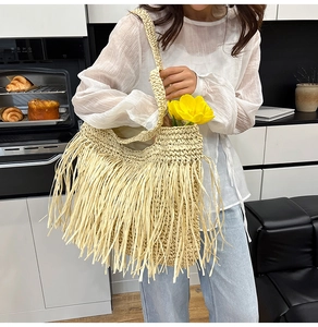 Détail d'un sac cabas en paille bohème avec de longues franges et des anses tressées