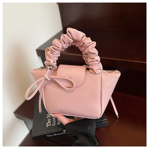Detailed view of pink pleated handbag with bow knot on vintage book background