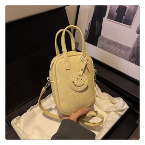 Close-up of lemon yellow litchi pattern leather mini bag with smiley face pendant