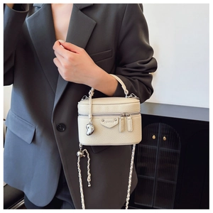 Details der beigen Box-Tasche mit Lychee-Narbung, Silberkette und Herzanhänger