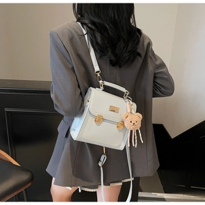 Detail of light blue PU leather backpack with gold push-locks and plush bear charm
