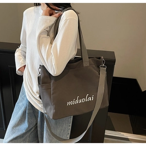 Close-up of charcoal canvas tote bag with white embroidery and adjustable strap