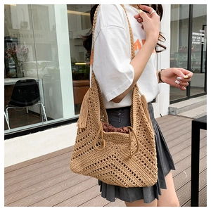 Detail view of khaki straw tote bag with V-shaped hollow weave and tassel detail