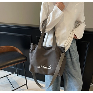 Detail view of large canvas tote bag showing the miduolai logo and side pocket