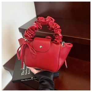 Detail of red ruched handle handbag with magnetic closure on vintage wooden background