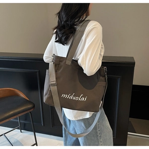 Detail of dark brown canvas tote bag with white embroidery and adjustable shoulder strap