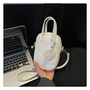 Detail of white litchi pattern mini handbag with silver hardware and smiley charm