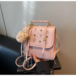 Close-up of pink faux leather backpack with bear prints, silk scarf, and plush charm