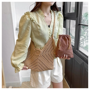 Detail of hand-woven vintage straw tote bag featuring geometric V-pattern and tassel charm
