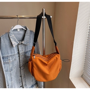 Detail of bright orange casual crossbody bag with multiple zippers and adjustable strap