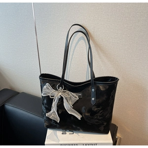 Detail der glänzenden schwarzen Tote Bag mit Perlen-Schleife auf minimalistischem Setup