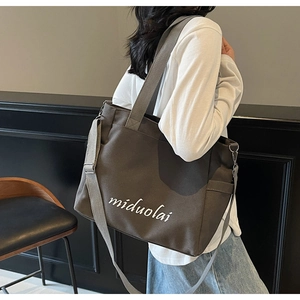 Detail of dark brown canvas tote bag featuring side pockets and a wide adjustable shoulder strap