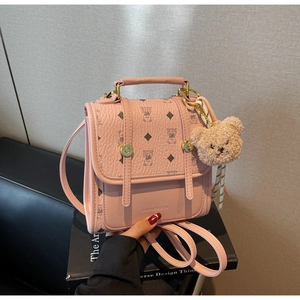 Detail of pink mini backpack featuring crown bear patterns and a plush charm