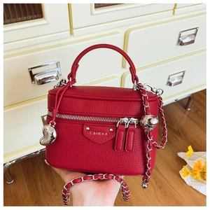 Detail der roten Box-Tasche aus Leder mit Kettenriemen und Metallanhängern im Lifestyle-Stil