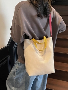 Sac seau minimaliste en toile crème avec poignées jaunes et bandoulière rouge vif