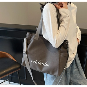 Detail of grey canvas tote bag featuring miduolai text and adjustable shoulder strap