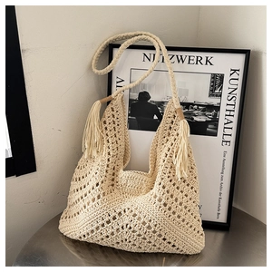 Detailed close-up of cream handmade crochet tote bag with boho tassels and knit pattern