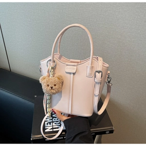 Close-up of pink bucket bag with smooth PU leather finish and cute plush bear charm