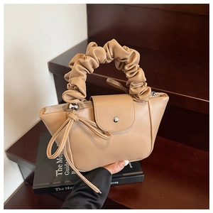 Detail of beige pleated handle shoulder bag with bow knot and metal snap closure