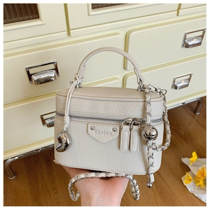 Detail der cremefarbenen Mini-Box-Tasche mit Litschistruktur und geflochtener Kette