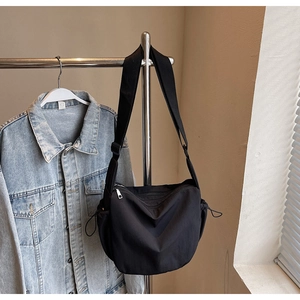Detail of black nylon crescent bag featuring adjustable drawstring and wide strap on a hanger