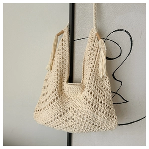 Detail of bohemian crochet tote bag featuring intricate openwork patterns and long tassels