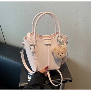 Detail of pink bucket bag with round handle, silver metal clasp and plush bear charm