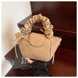 Close-up of beige ruched handle handbag with elegant tassel and magnetic flap closure