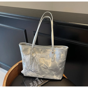 Detailaufnahme der silbernen Shopper-Tasche mit Metallic-Effekt und Schleifenanhänger