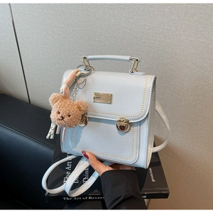Detail of light blue PU leather backpack with pearl trim and cute bear charm