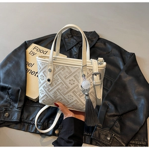 Detailed close-up of beige bucket bag featuring geometric patterns and a long grey tassel