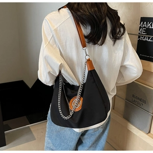 Detail of black and white contrast shoulder bag with brown leather strap and silver chain