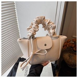 Detail of cream pleated handle bag with magnetic flap and long leather tassels