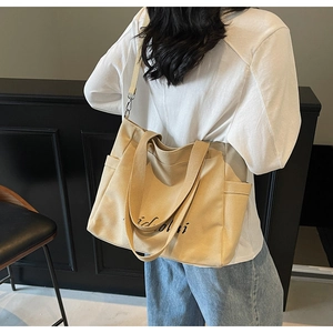 Detail of beige canvas tote bag showing side pockets, idoli print, and adjustable strap