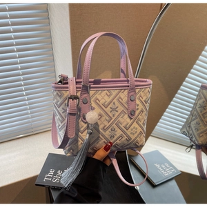 Detail of a mini cream brocade bucket bag with purple floral patterns and stone tassel