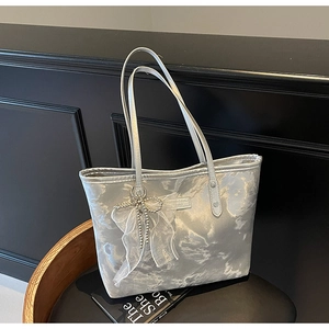 Detail der silbernen Metallic-Tasche mit Netzschleife und Perlenquasten-Anhänger