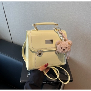 Close-up of yellow vintage bag with pearl trim and cute brown plush bear charm
