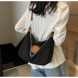 Detail of the high-quality black canvas hobo bag with a silver M logo and chain