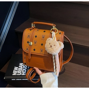 Detailed texture of brown vintage backpack with bear patterns and plush bear charm