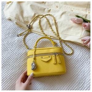 Detail der gelben Leder-Vanity-Bag mit Kettenriemen und Herzanhänger-Verzierung